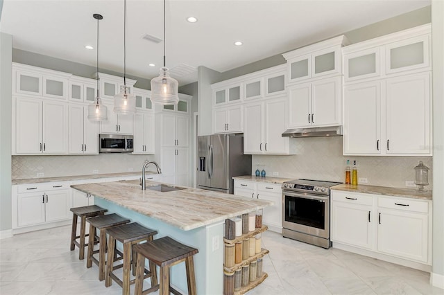 kitchen with stainless steel appliances, white cabinets, a kitchen island with sink, and sink