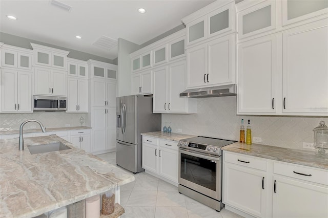 kitchen with light stone countertops, stainless steel appliances, sink, and white cabinetry