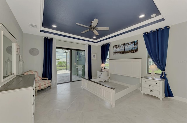 bedroom featuring ceiling fan, a tray ceiling, and access to outside