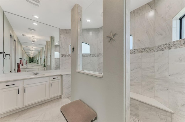 bathroom with tiled shower and vanity