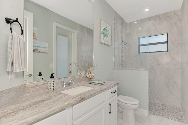 bathroom with toilet, vanity, and tiled shower