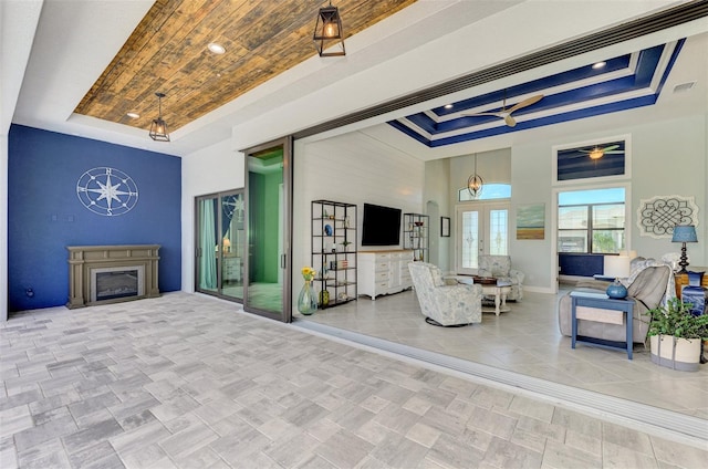 living room with a towering ceiling, a tray ceiling, and ceiling fan