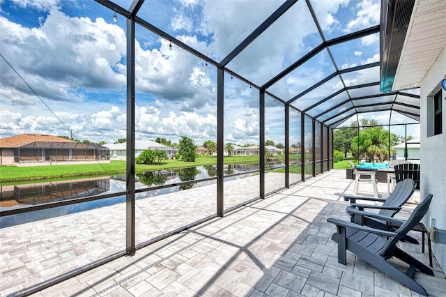 view of patio / terrace featuring glass enclosure and a water view