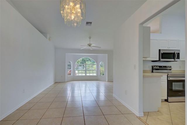 spare room featuring ceiling fan with notable chandelier, vaulted ceiling, and light tile patterned floors