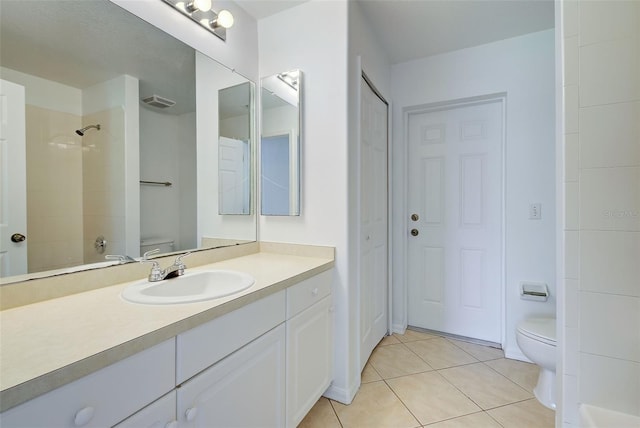 bathroom with tiled shower, vanity, toilet, and tile patterned floors