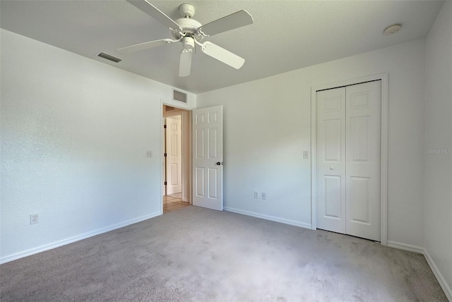 unfurnished bedroom featuring ceiling fan, a closet, and light carpet