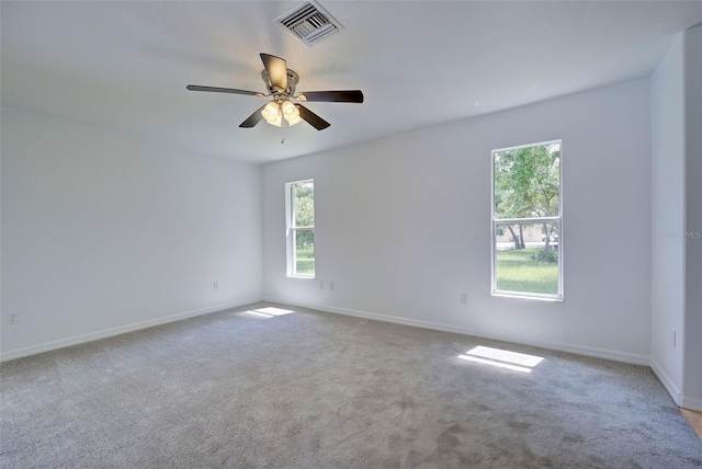 carpeted spare room featuring a wealth of natural light and ceiling fan