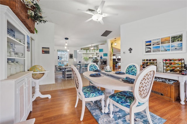 dining room with ceiling fan, light hardwood / wood-style floors, and vaulted ceiling