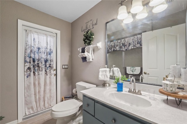 bathroom featuring toilet, vanity, curtained shower, an inviting chandelier, and hardwood / wood-style flooring