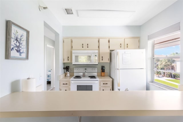 kitchen featuring cream cabinetry and white appliances