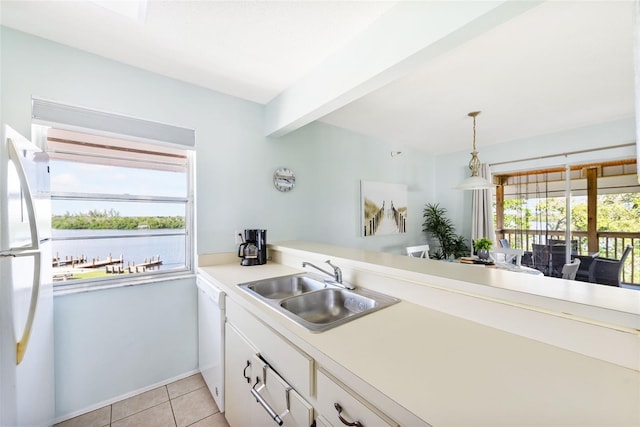 kitchen with hanging light fixtures, white cabinets, sink, and a wealth of natural light