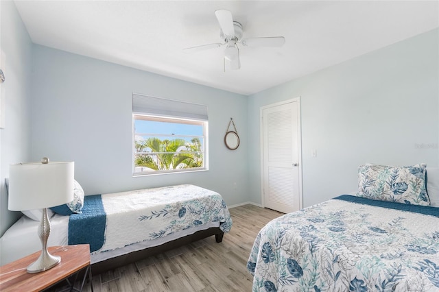 bedroom with light wood-type flooring, ceiling fan, and a closet