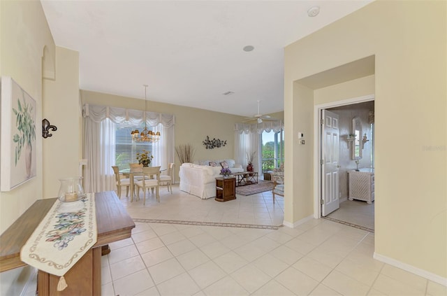 tiled living room with ceiling fan with notable chandelier