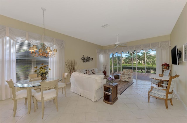 tiled living room with a wealth of natural light and ceiling fan with notable chandelier