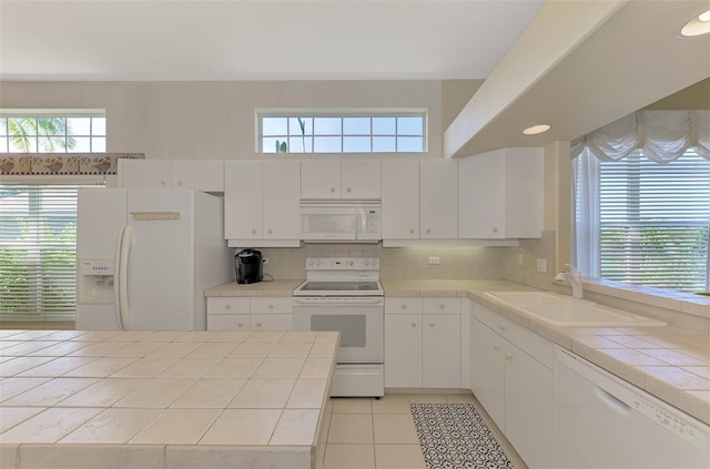 kitchen with white cabinets, white appliances, and tile counters