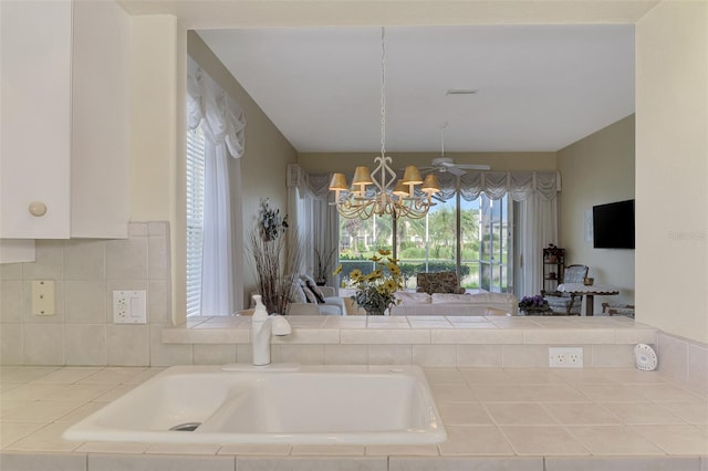 kitchen with decorative light fixtures, white cabinets, ceiling fan with notable chandelier, and tile counters