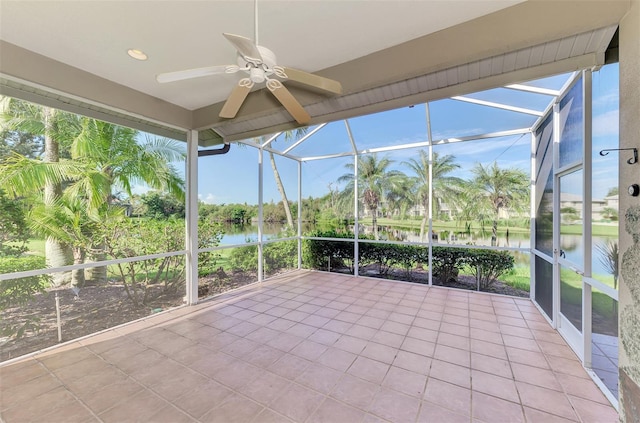 unfurnished sunroom featuring a water view, ceiling fan, and a healthy amount of sunlight