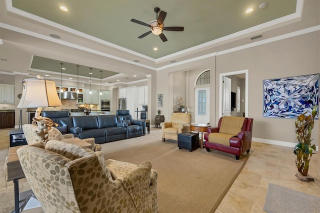 living room featuring a raised ceiling, crown molding, and ceiling fan