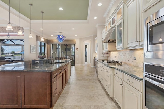 kitchen with appliances with stainless steel finishes, hanging light fixtures, sink, and dark stone counters