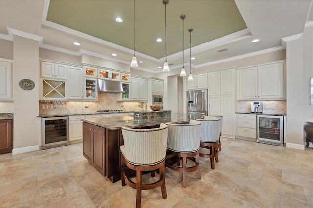 kitchen featuring appliances with stainless steel finishes, white cabinetry, beverage cooler, a center island with sink, and extractor fan