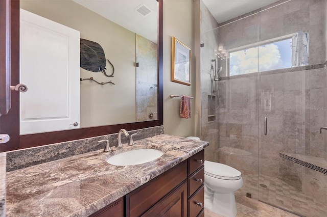 bathroom featuring vanity, a shower with shower door, and toilet