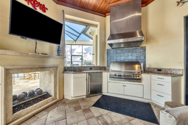 kitchen featuring white cabinetry, wall chimney exhaust hood, crown molding, wooden ceiling, and stainless steel fridge