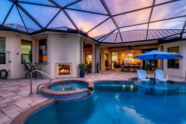 view of swimming pool featuring a patio, glass enclosure, and an in ground hot tub