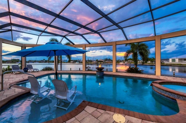 pool at dusk with a water view, an in ground hot tub, a patio area, and glass enclosure