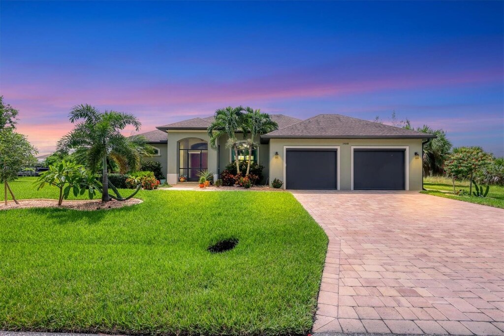 15608 Lakeland Cir, Port Charlotte, FL 33981 - view of front of home with a lawn, decorative driveway, a garage, and stucco siding