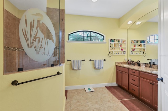 bathroom with vanity, a tile shower, and a healthy amount of sunlight