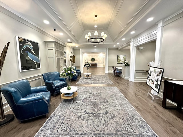 living room with crown molding, wood-type flooring, ornate columns, and a notable chandelier