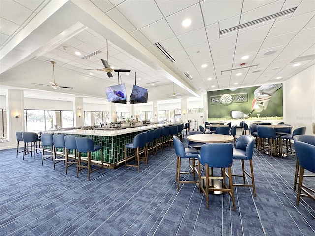 interior space with ceiling fan, dark colored carpet, and bar