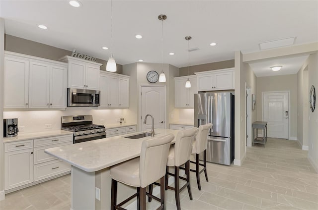 kitchen featuring sink, white cabinetry, hanging light fixtures, stainless steel appliances, and a kitchen island with sink