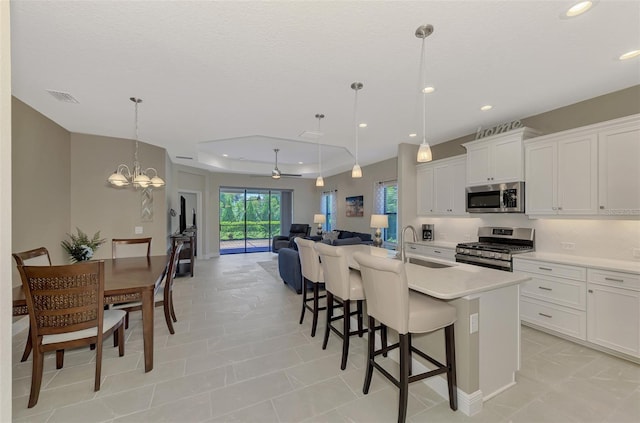 kitchen featuring white cabinetry, sink, hanging light fixtures, a kitchen island with sink, and stainless steel appliances