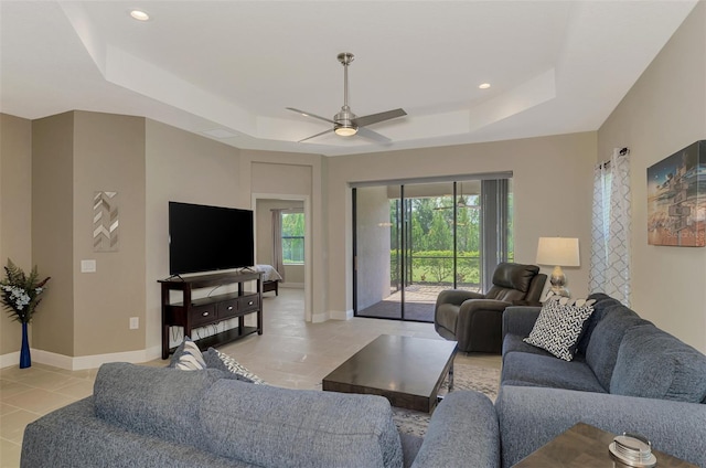 tiled living room featuring ceiling fan and a raised ceiling