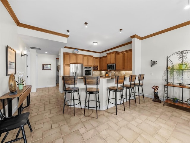 kitchen with kitchen peninsula, a kitchen bar, decorative backsplash, stainless steel appliances, and ornamental molding