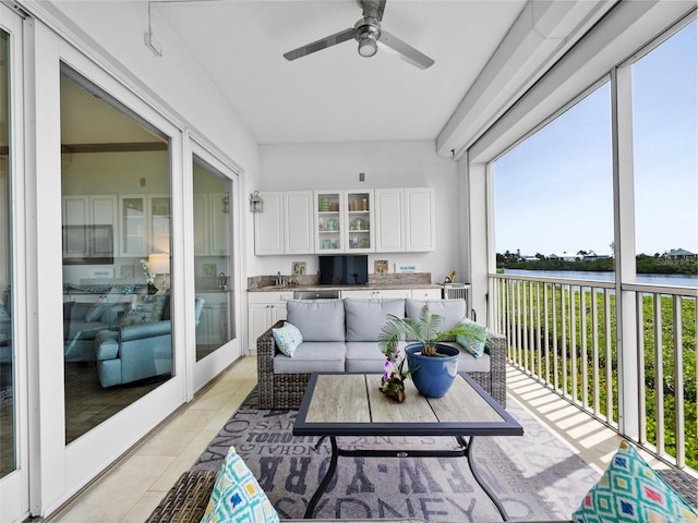 sunroom / solarium with ceiling fan, sink, and a water view