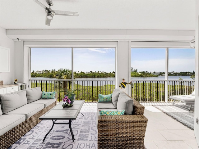 tiled living room with ceiling fan and a water view