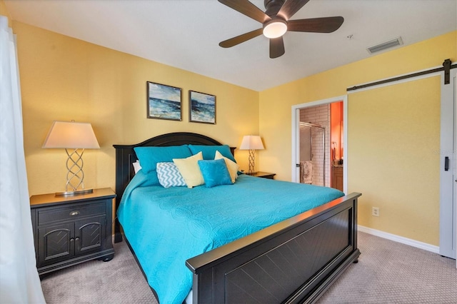 bedroom with a barn door, connected bathroom, light carpet, and ceiling fan