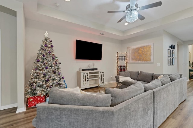 living room featuring a tray ceiling, ceiling fan, and hardwood / wood-style flooring