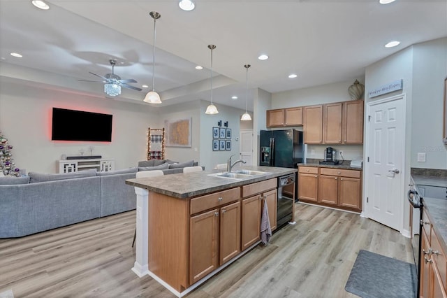 kitchen with a center island with sink, black appliances, sink, ceiling fan, and light wood-type flooring