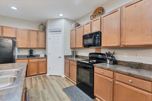 kitchen with black appliances, sink, and light wood-type flooring