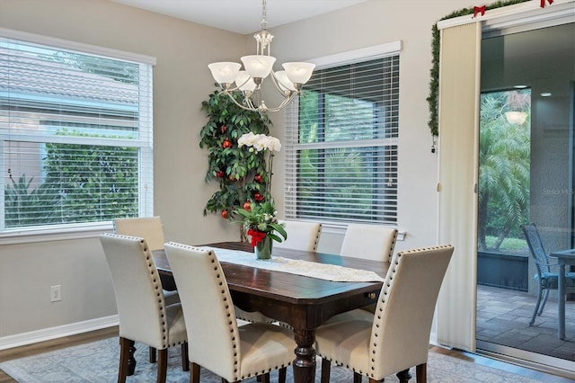 dining space with a healthy amount of sunlight, hardwood / wood-style floors, and a notable chandelier