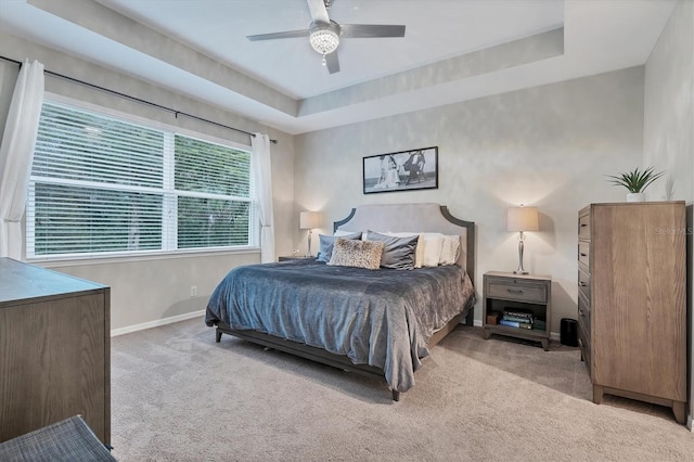 carpeted bedroom with a tray ceiling and ceiling fan