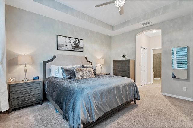 carpeted bedroom with a closet, ceiling fan, and ensuite bath