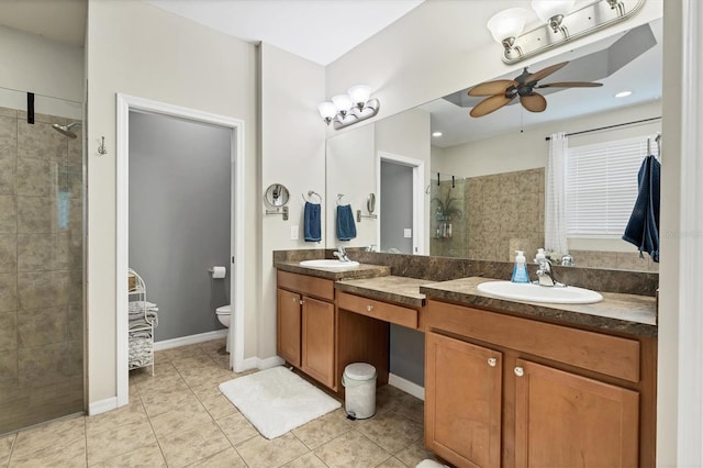 bathroom with vanity, toilet, ceiling fan, and a tile shower