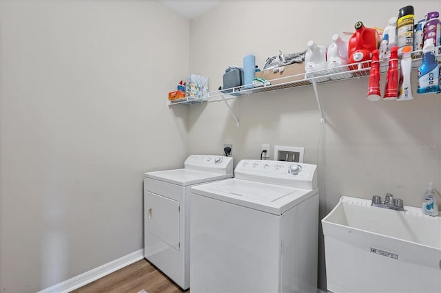 clothes washing area featuring washer and clothes dryer, sink, and hardwood / wood-style floors