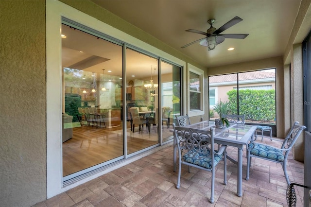 sunroom featuring ceiling fan with notable chandelier