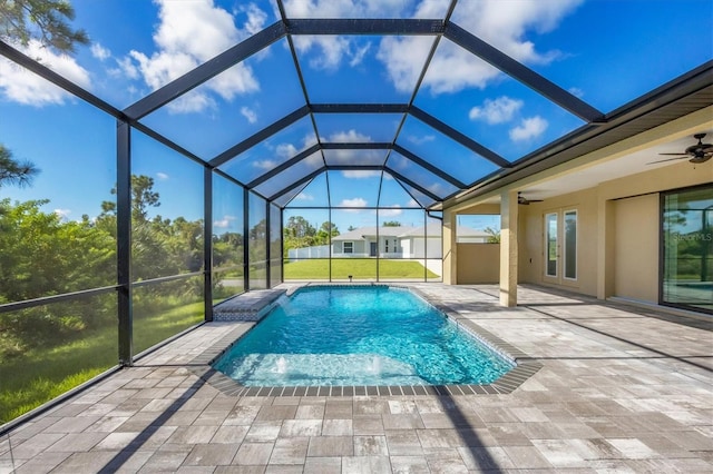 view of swimming pool featuring ceiling fan, a patio, pool water feature, a yard, and glass enclosure