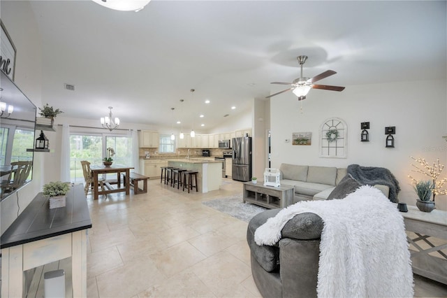 tiled living room with ceiling fan with notable chandelier, lofted ceiling, and sink